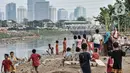 Anak-anak bermain di bantaran Kanal Banjir Barat dengan latar belakang gedung pencakar langit di Jakarta, Kamis (6/8/2020). Badan Pusat Statistik mencatat pertumbuhan ekonomi Indonesia Kuartal II/2020 minus 5,32 persen akibat perlambatan sejak adanya pandemi COVID-19. (merdeka.com/Iqbal S. Nugroho)