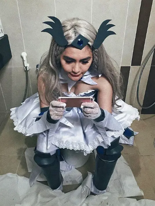 Artis sekaligus selebgram Angela Lee berpose di toilet sambil bermain handphone dalam balutan busana cosplay. (Instagram/angelalee87)