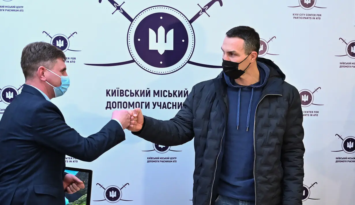 Mantan petinju Ukraina Wladimir Klitschko (kanan) menyapa seorang anggota staf setelah mendaftar sebagai tentara cadangan di pusat perekrutan relawan di Kiev, 2 Februari 2022. Wladimir beralasan cinta tanah air sehingga memaksanya untuk mempertahankan kemerdekaan Ukraina. (Genya SAVILOV/AFP)