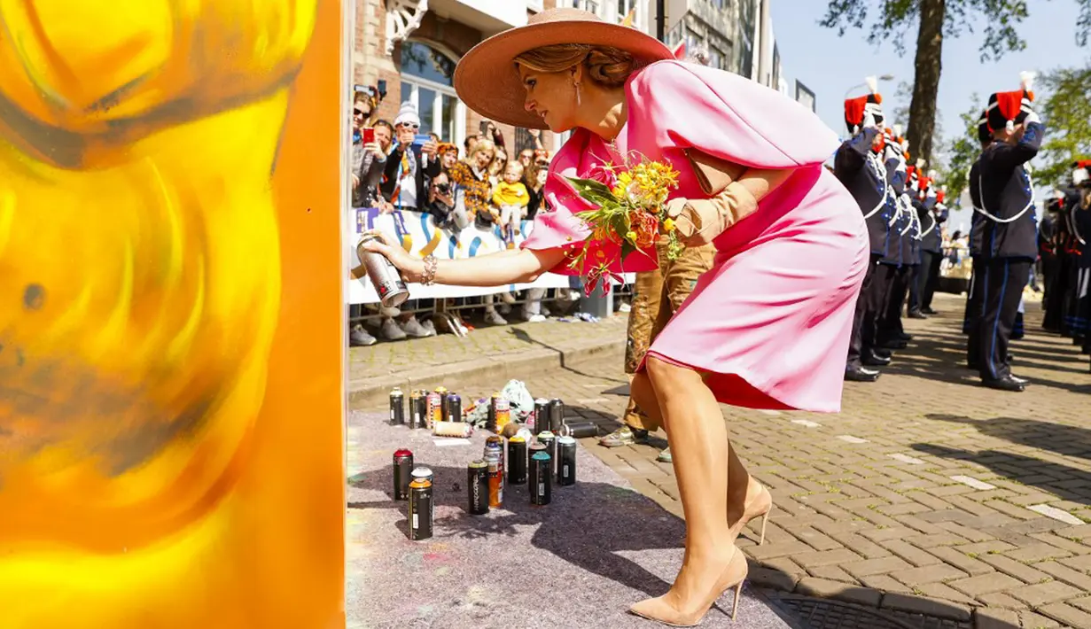 <p>Ratu Belanda Maxima menyemprotkan cat pada mural saat perayaan Hari Raja di Maastricht, Belanda, Rabu (27/4/2022). Setelah dua tahun hening karena pandemi COVID-19, Belanda kembali merayakan Hari Raja seperti biasa. (Remko de Waal/ANP/AFP)</p>