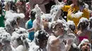 Orang tua dan anak-anak disemprot dengan busa oleh petugas pemadam kebakaran selama pesta di distrik Malasana Madrid, Spanyol, (4/5/2019). (AP Photo/Paul White)