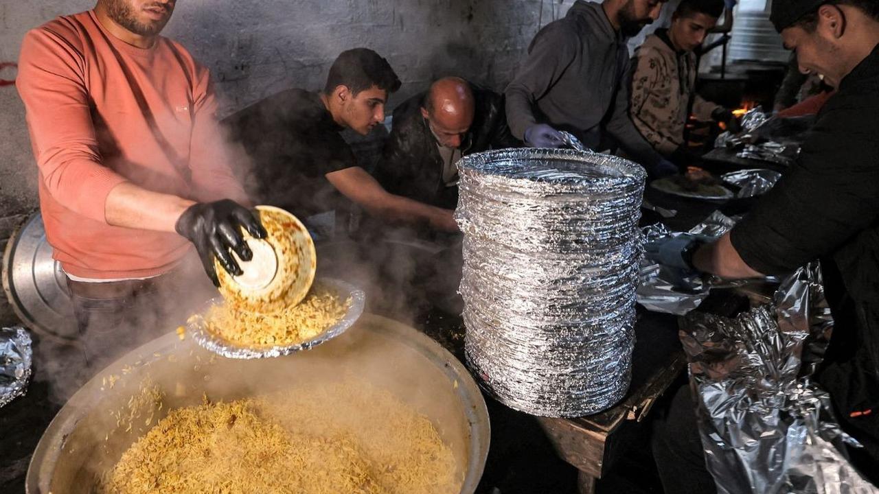 Hidangan itu dimasak oleh relawan dari organisasi kemanusiaan yang juga seorang pengungsi Barbara yang menyajikan makanan bagi orang-orang yang berbuka puasa di bulan suci Ramadan di Rafah. Foto: MOHAMMED ABED / AFP