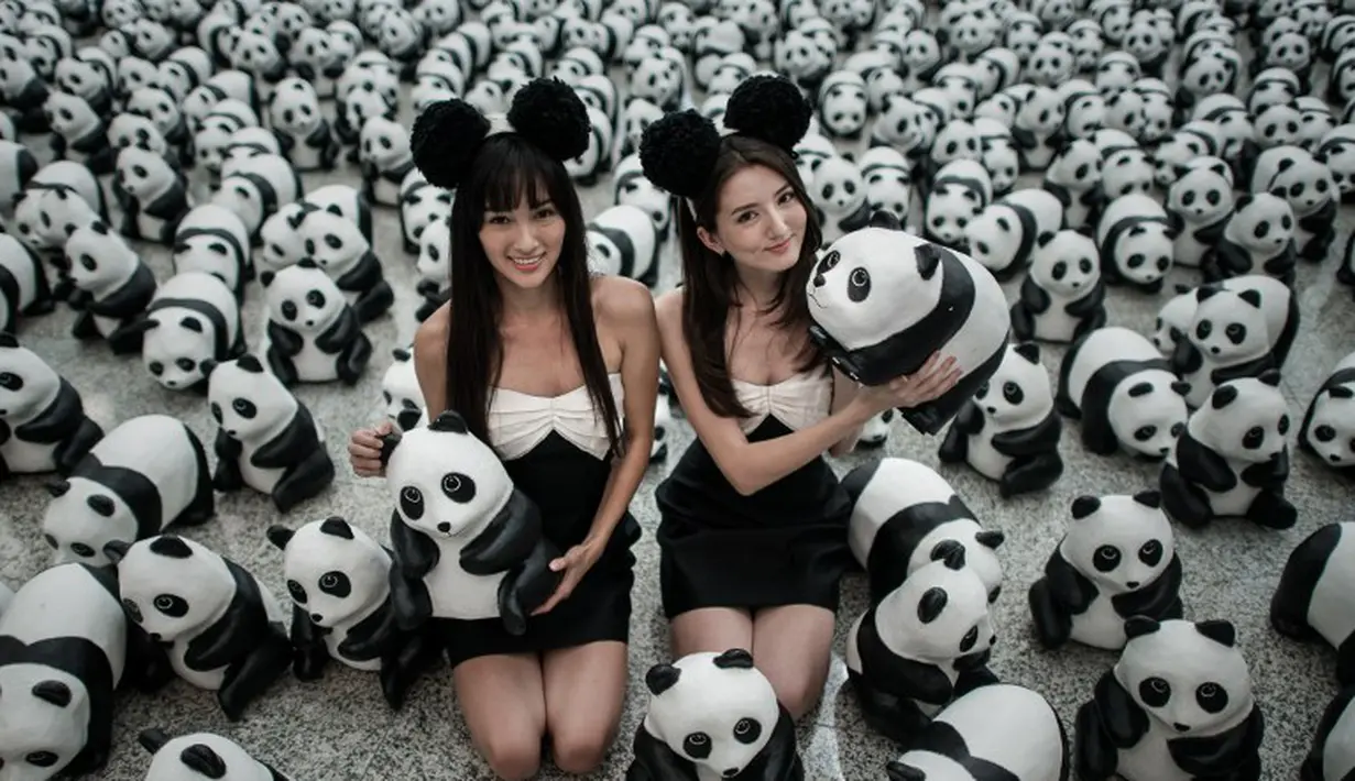 Para model berkostum hitam putih tampak berfoto dengan ribuan panda di Bandara Internasional Hong Kong, Senin (9/6/14). (AFP PHOTO/Philippe Lopez)