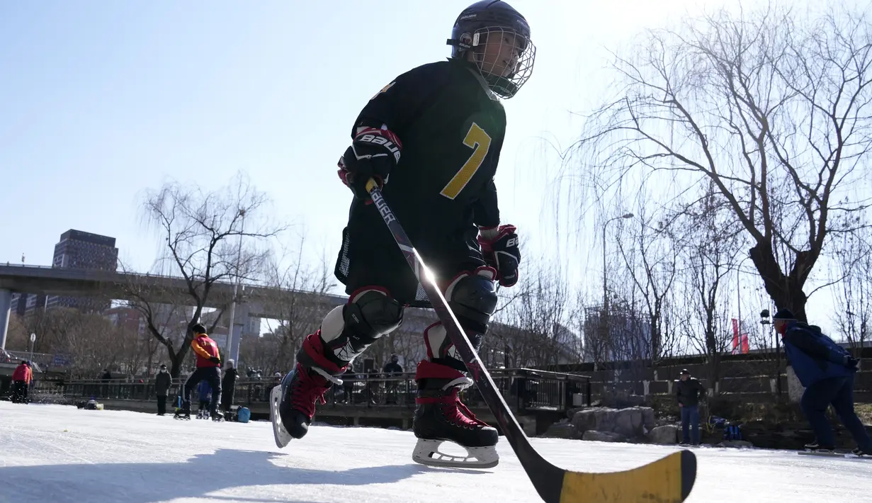 Seorang anak bermain hoki es di kanal yang membeku saat Olimpiade Musim Dingin 2022 hampir berakhir di Beijing pada Sabtu, 19 Februari 2022. (AP Photo/Ng Han Guan)