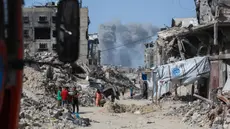 Asap mengepul ke arah utara menjadi latar ketika warga Palestina bergerak melalui Jabalia meninggalkan Jalur Gaza utara menuju Kota Gaza pada 19 Mei 2025. (Bashar TALEB/AFP)