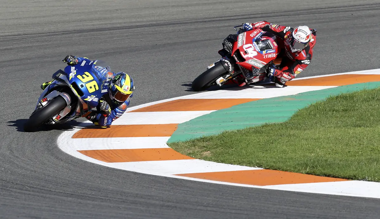 Pembalap Suzuki Ecstar, Joan Mir saat berada di depan Andrea Dovizioso dari Tim Ducati pada balapan MotoGP Valencia di Sirkuit Ricardo Tormo, Spanyol (15/11/2020). Tambahan 9 poin hasil finis ketujuh pada MotoGP Valencia membuat pebalap tim Suzuki Ecstar mengoleksi nilai 171. (AP Photo/Alberto Saiz)