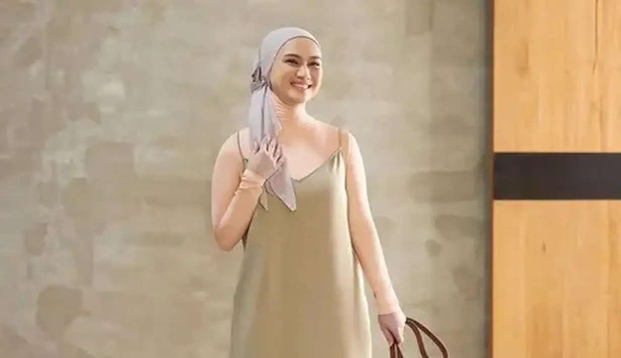 Melody tampil dengan kerudung turban dipadukan inner turtleneck pink serta spaghetti strap waena hijau. Sambil membawa tas coklat dan mengenakan heels tertutupnya. [@melodylaksani92]