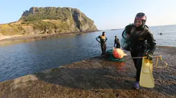 Haenyeo Korea Selatan keluar dari air setelah menangkap kerang dan abalone di pulau Jeju, 23 November 2018. Menyelam kurang lebih sampai kedalaman 20 meter, para perempuan perkasa ini tidak menggunakan tabung oksigen. (AP/Ahn Young-joon)