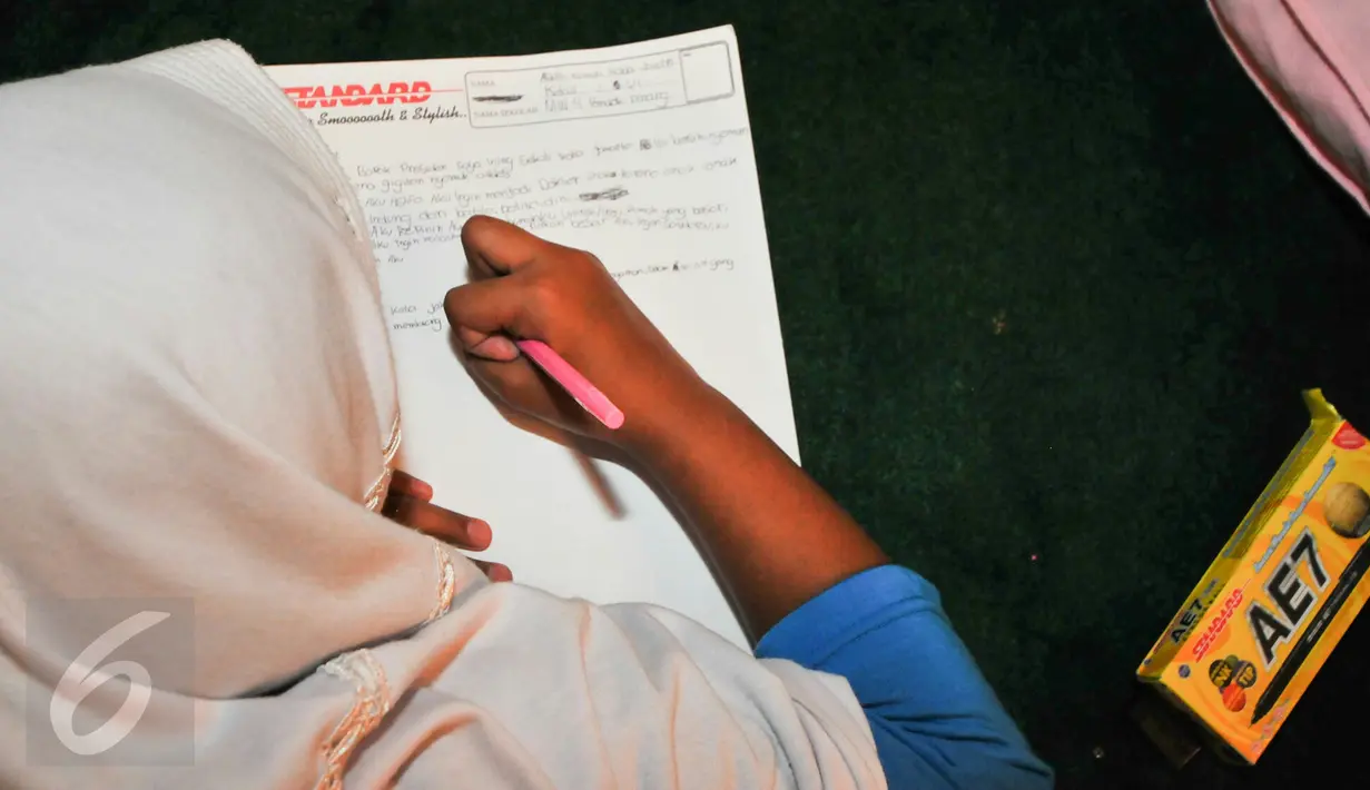 Seorang anak yatim menulis surat untuk Presiden Jokowi di TMII, Jakarta, Minggu (19/6). Disela-sela kegiatan berbuka puasa bersama, anak-anak belajar menuliskan harapan, cita-cita yang dituangkan dalam surat untuk Presiden RI. (Liputan6.com/Yoppy Renato)