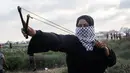 Wanita Palestina memakai ketapel untuk melemparkan batu ke arah pasukan Israel saat bentrok di Khan Yunis, Jalur Gaza, Jumat (13/9/2019). Warga berunjuk rasa dalam aksi damai Great March of Return di Jalur Gaza. (SAID KHATIB/AFP)