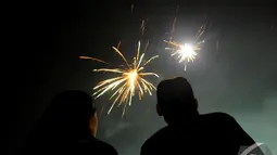 Dua orang pengunjung melihat kembang api yang memancar di malam pergantian tahun, Ancol, Jakarta, Kamis (1/1/2015). (Liputan6.com/Faisal R Syam)