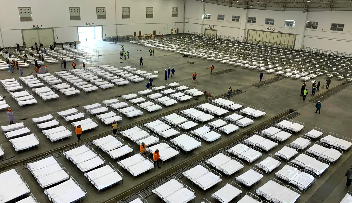 Para pekerja mengatur tempat tidur di pusat konvensi yang diubah menjadi rumah sakit sementara virus corona, Wuhan, Provinsi Hubei, China, Selasa (4/2/2020). Jumlah pasien virus corona saat ini telah melewati 20 ribu orang. (Chinatopix via AP)