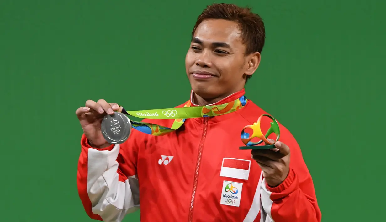Lifter Indonesia, Eko Yuli Irawan berpose dengan medali perak di atas podium cabang olahraga angkat besi 62 KG selama Olimpiade 2016 di Rio De Janeiro, Senin (8/8). Atlet Eko Yuli mempersembahkan medali perak bagi kontingen Indonesia. (GOH Chai Hin/AFP)