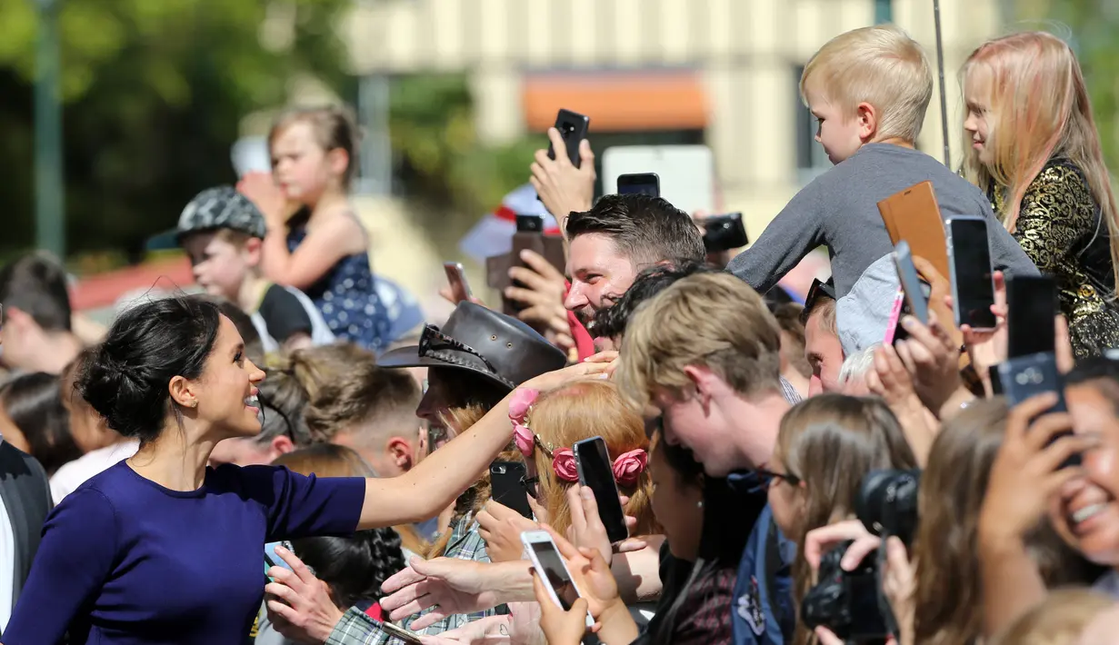 Duchess of Sussex, Meghan Markle menyalami anak kecil saat berjalan di Taman Pemerintah Rotorua, Selandia Baru, Rabu (31/10). Meghan dan Pangeran Harry sedang dalam tur tiga minggu di Australia, Selandia Baru, Tonga, dan Fiji. (Michael Bradley/Pool/AFP)
