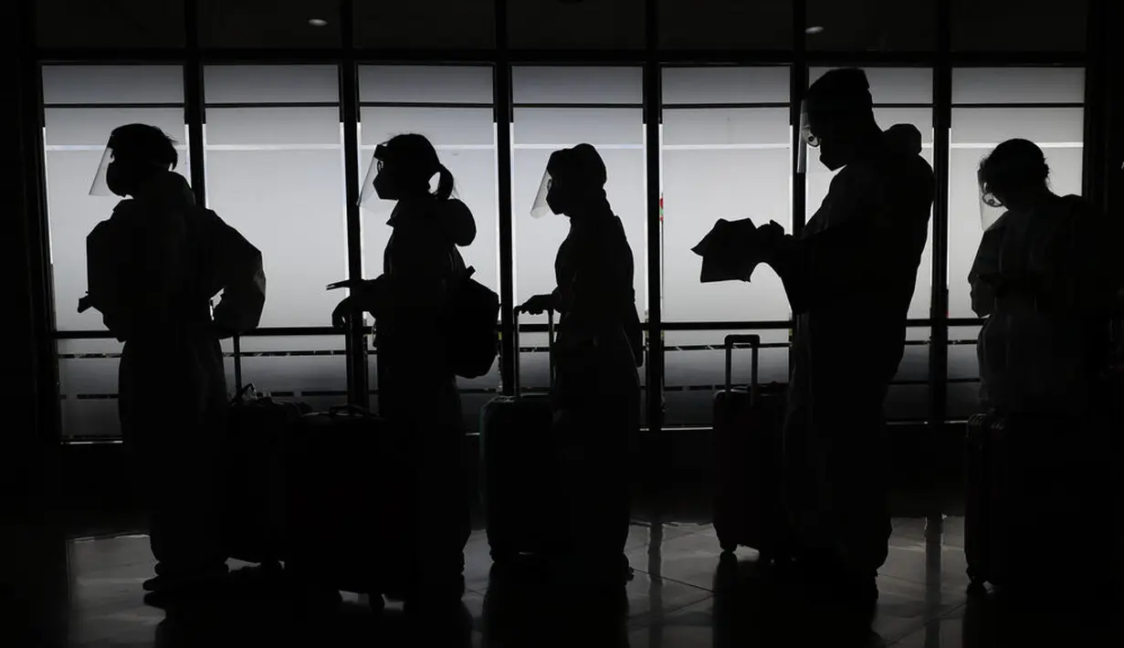 Penumpang asing yang mengenakan pakaian pelindung bersiap untuk penerbangan mereka ke China di Bandara Internasional Manila, Filipina, Senin (18/1/2021). Infeksi virus corona COVID-19 di Filipina telah melonjak melewati 500 ribu kasus.  (AP Photo/Aaron Favila)