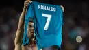 Pemain Real Madrid, Cristiano Ronaldo mengangkat jerseynya tinggi-tinggi di hadapan suporter Camp Nou pada leg pertama Piala Super Spanyol, Senin (14/8). Aksi selebrasi Ronaldo usai mencetak gol ke gawang Barcelona itu menjadi sorotan. (STRINGER/AFP)