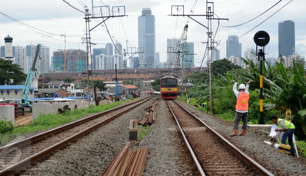Kereta milintas di dekat proyek pembangunan jalur dua rel ganda atau double-double track (DDT) Manggarai-Cikarang, Jakarta, Jumat (13/1). Menhub mengungkapkan, kendala proyek DDT ini adalah administrasi pembebasan lahan. (Liputan6.com/Gempur M Surya)