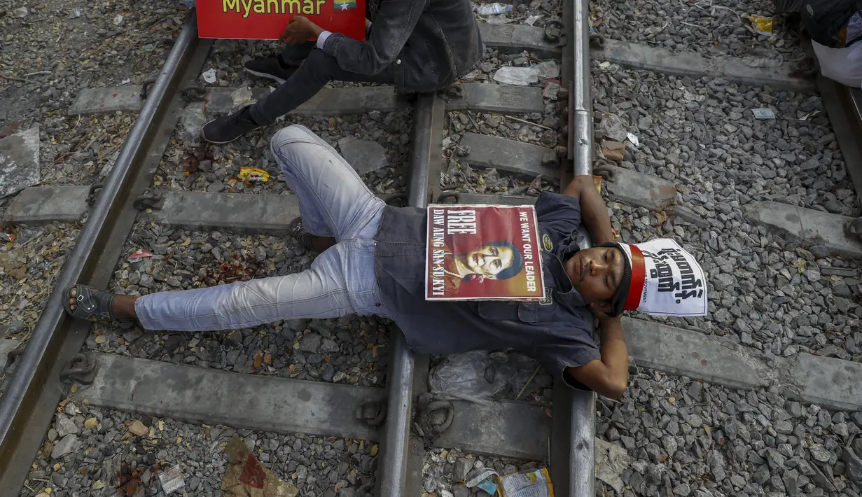 Seorang demonstran beristirahat di rel kereta api dalam upaya mengganggu layanan kereta selama protes terhadap kudeta militer di Mandalay, Myanmar (17/2/2021). Demonstran di Myanmar berkumpul dalam jumlah terbesar untuk memprotes kudeta militer. (AP Photo)