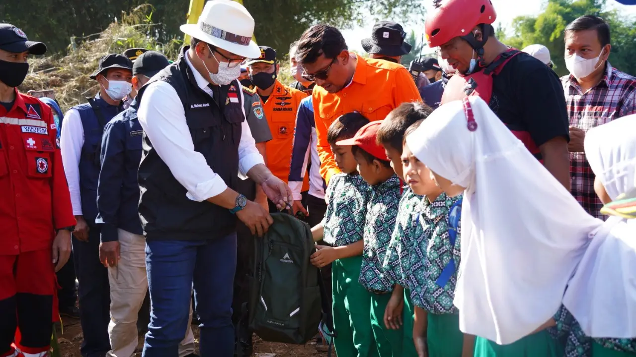 Gubernur Jabar Ridwan Kamil didampingi Wabup Garut Helmi Budiman memberikan paket tas sekolah bagi anak-anak korban terdampak banjir di Kampung Cikarokrok, Desa Sukasenang, Kecamatan Banyuresmi. (Liputan6.com/Jayadi Supriadin)