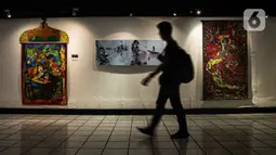 Pengunjung melewati lukisan yang ditampilkan dalam pameran bertajuk "Hai, Kamu!" di Balai Budaya, Jakarta, Kamis (4/11/2021). Pameran untuk mengenang penyair WS Rendra (1935-2009) ini menampilkan 19 karya dari 15 pelukis yang terinspirasi dari karya puisi WS Rendra. (Liputan6.com/Faizal Fanani)