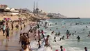 Warga Palestina bermain air di pantai Beit Lahia di Jalur Gaza utara saat para siswa memulai liburan musim panas mereka pada 3 Juni 2022. Sejumlah warga menikmati musim panas dengan berenang dan bermain air di pantai. (MOHAMMED ABED / AFP)