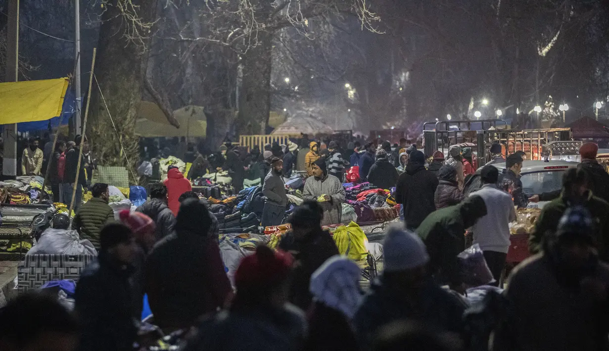 Pembeli berkerumun untuk membeli pakaian hangat di pasar terbuka pada hari yang dingin di Srinagar, Kashmir yang dikuasai India, Minggu (26/12/2021). (AP Photo/Mukhtar Khan)