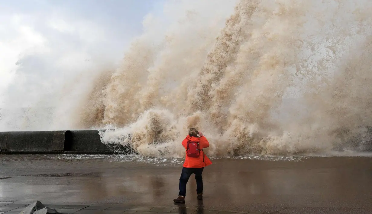 Seorang wanita mengambil gambar ombak yang disebabkan badai Eleanor di sepanjang pinggir laut di New Brighton, Inggris barat laut (3/1). Setelah melanda Inggris, badai Eleanor bergerak ke Prancis, Belgia dan Belanda. (AFP Photo/Paul Ellis)