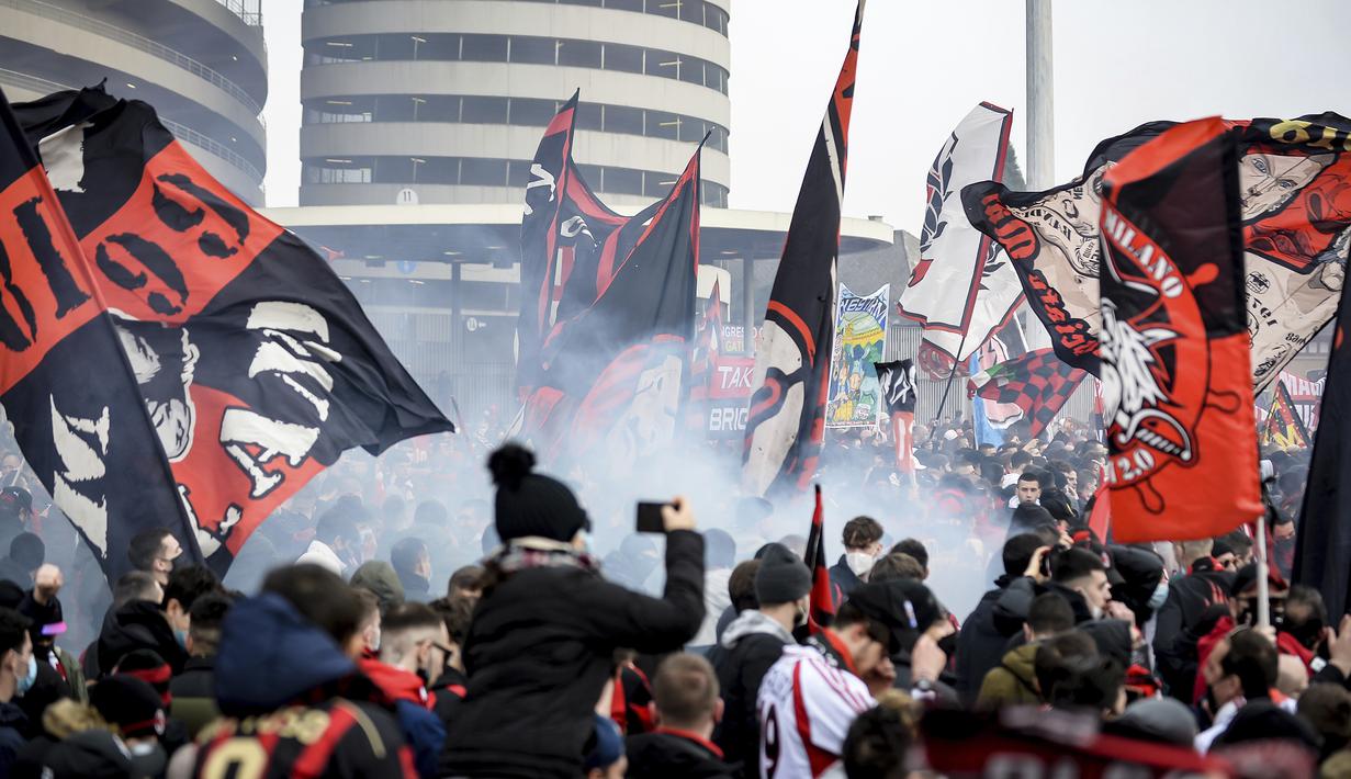 Para pendukung AC Milan mengibarkan bendera dan menyalakan flare di luar Stadion San Siro sebelum dimulainya laga lanjutan Liga Italia 2020/21 antara AC Milan melawan Inter Milan, Minggu (21/2/2021). AC Milan kalah 0-3 dari Inter Milan. (LaPresse via AP/Claudio Furlan)