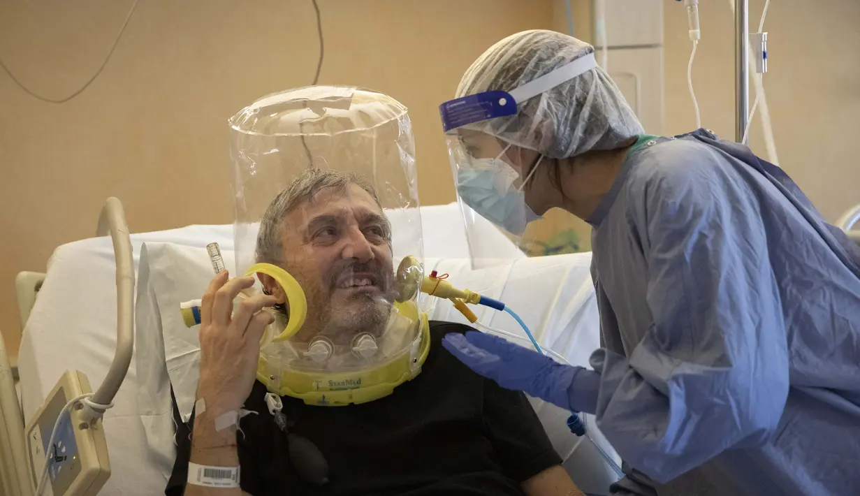 Nazzareno Santilli, 60 tahun, menghirup ventilasi tutup kepala oksigen CPAP tersenyum kembali kepada Dr. Elisabetta Teti di unit COVID-19 sub-intensif Rumah Sakit Poliklinik Tor Vergata, di Roma, 7 November 2020. (AP Photo/Alessandra Tarantino)