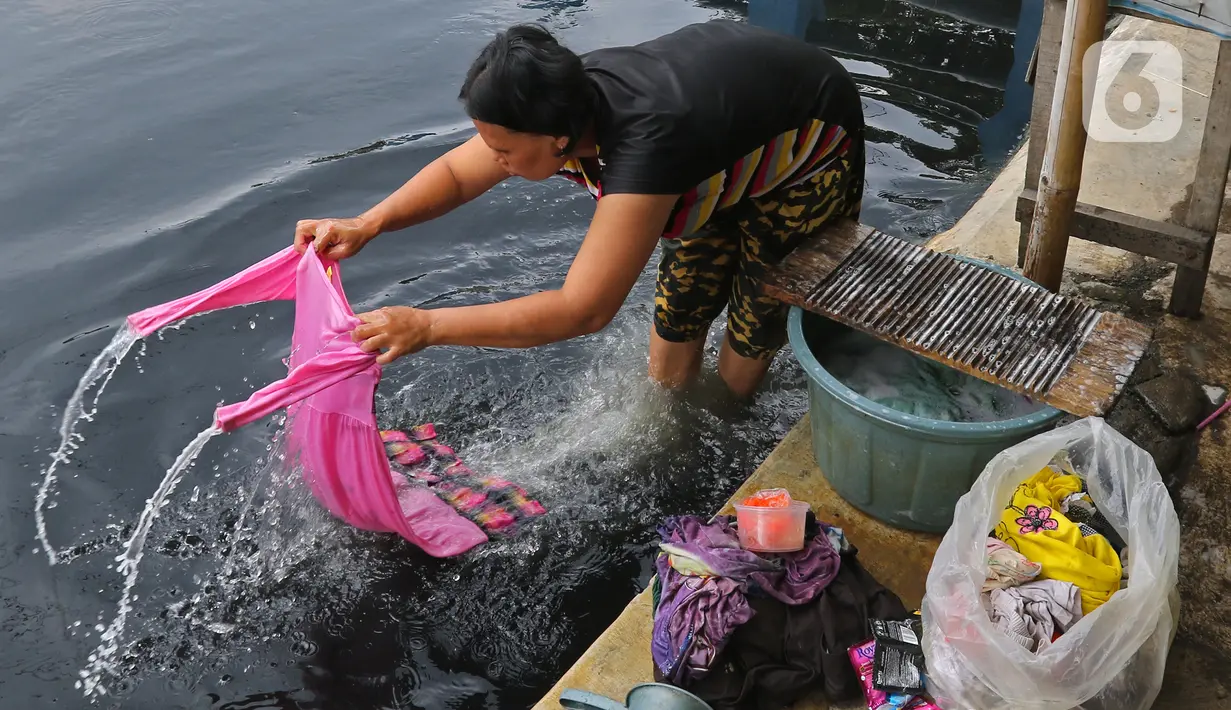 Warga mencuci pakaian di Kali Cilemahabang yang menghitam di kawasan Karangbahagia, Kabupaten Bekasi, Jawa Barat, Selasa (7/9/2021). Warga memanfaatkan aliran Kali Cilemahabang yang menghitam dan mengeluarkan bau tak sedap untuk mencuci baju hingga mandi. (Liputan6.com/ Herman Zakharia)