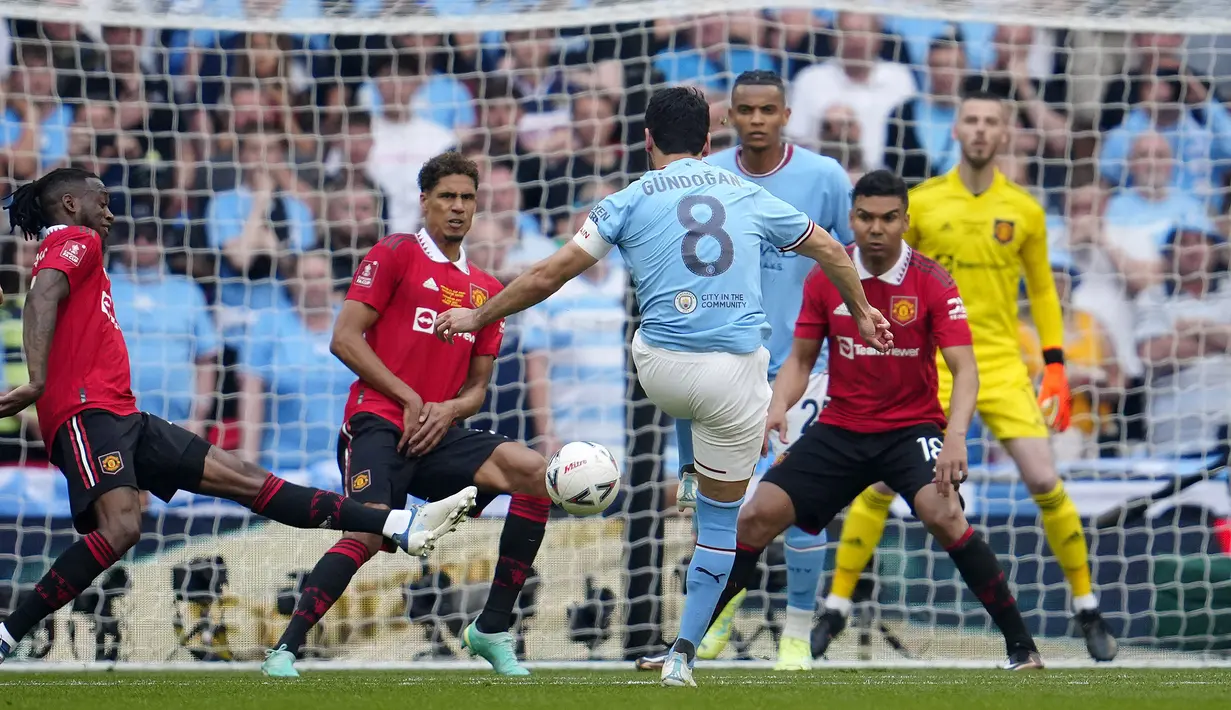Pemain Manchester City, Ilkay Gundongan (tengah), menendang bola ke gawang Manchester United  yang membuahkan gol kedua dalam pertandingan final FA Cup 2022/2023 yang berlangsung di Wembley Stadium, Sabtu (3/6/2023). (AP Photo/Dave Thompson)