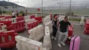 Calon penumpang pesawat berjalan menuju Bandara Internasional Hong Kong melewati barikade yang dibuat oleh demonstran (1/9/2019). (AP Photo/Kin Cheung)