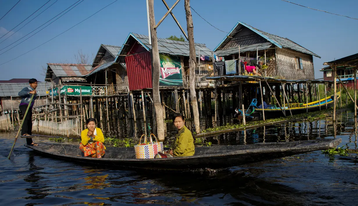 Masyarakat melewati rumah-rumah panggung menggunakan perahu di kampung terapung Danau Inle, Negara Bagian Shan, Myanmar, Senin (18/2). Seluruh kehidupan warga praktis berhubungan dengan perairan Danau Inle. (Ye Aung THU/AFP)