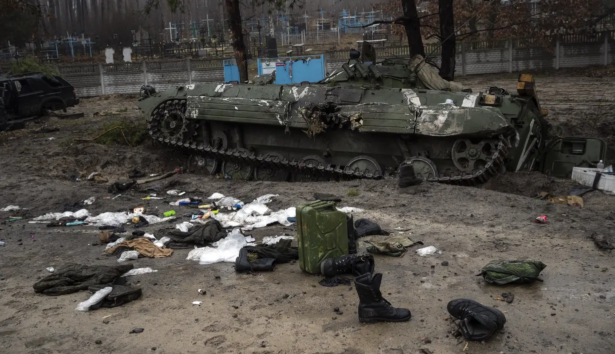 Perlengkapan militer yang ditinggalkan tentara Rusia berserakan di dekat sebuah tank saat dilakukan penyisiran militer oleh tentara Ukraina setelah penarikan pasukan Rusia dari daerah di pinggiran Kiev, Ukraina, Jumat, 1 April 2022. (AP Photo/Rodrigo Abd)