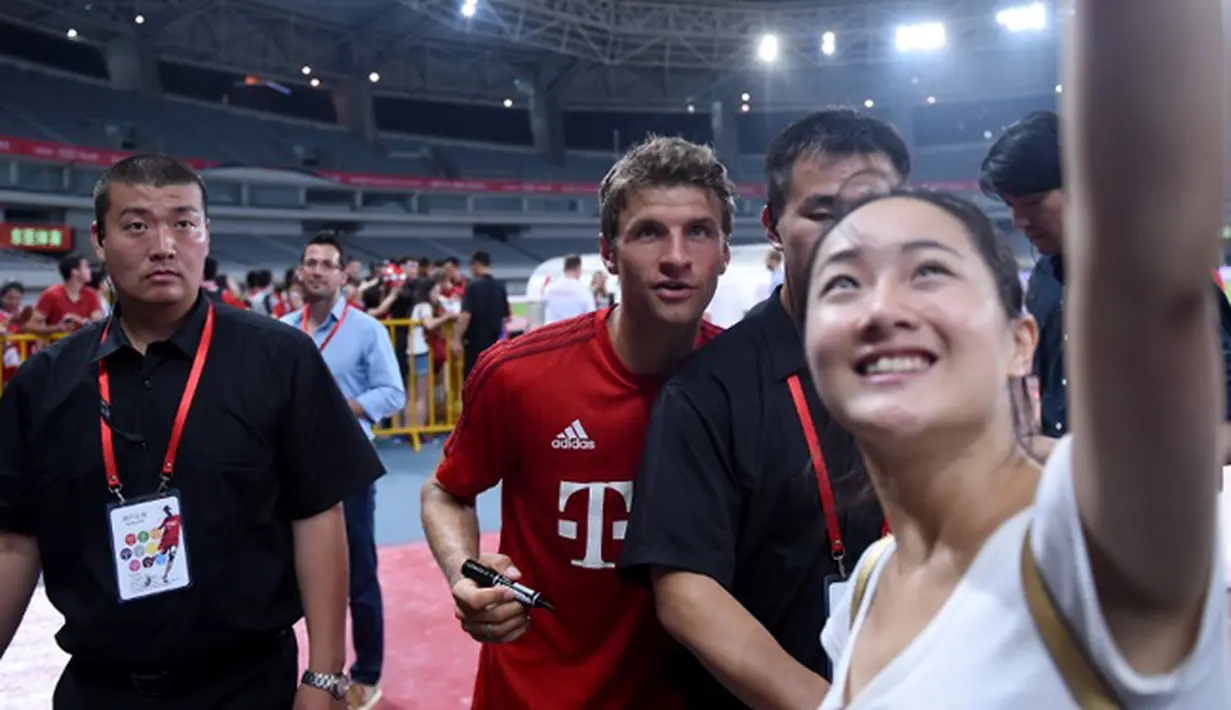 Penyerang Bayern Muenchen, Thomas Mueller berselfie bersama seorang fans usai sesi latihan di Shanghai, China, (19/7/2015). Bayern mengunjungi Cina untuk menggelar Tur Pra-musim. (AFP PHOTO/JOHANNES EISELE)