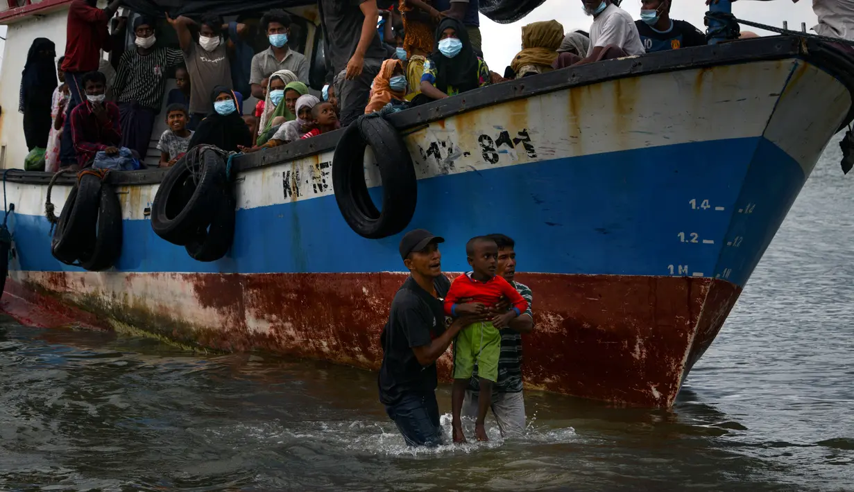 Nelayan Aceh membantu evakuasi seorang anak pengungsi etnis Rohingya menuju pesisir pantai desa Lancok, di Kabupaten Aceh Utara, Kamis (25/6/2020). Hampir 100 orang etnis Rohingya, termasuk 30 orang anak-anak ditemukan terdampar di tengah laut dengan kondisi kapal rusak. (CHAIDEER MAHYUDDIN/AFP)