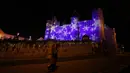 Dua orang berjalan melewati proyeksi Natal di Kastil Steen di pusat bersejarah Antwerpen, Belgia, 20 Desember 2021. Negara-negara di Eropa mempertimbangkan pembatasan yang lebih ketat guna membendung gelombang baru infeksi COVID-19 yang didorong oleh varian omicron. (AP Photo/Virginia Mayo)