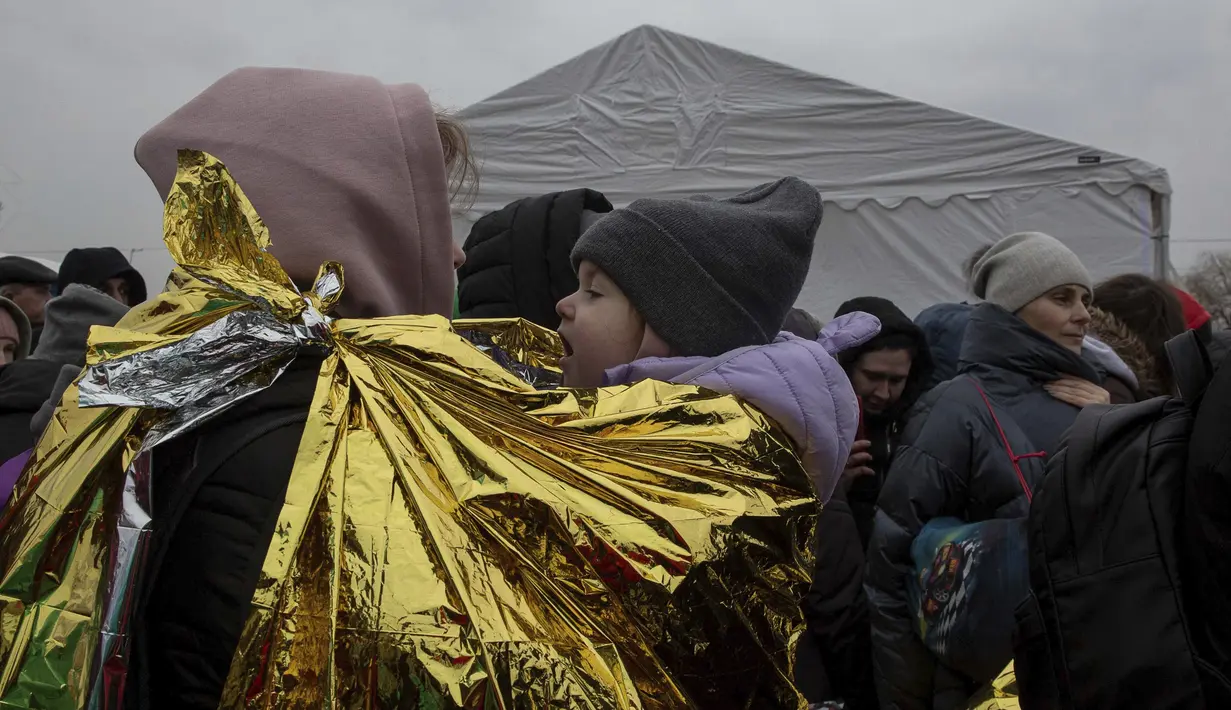 Seorang perempuan menggendong anak yang terbungkus selimut termal setelah melarikan diri dari Ukraina dan tiba di perbatasan di Medyka, Polandia, Senin (7/3/2022). Hampir 2 juta orang melarikan diri dari Ukraina sejak invasi Rusia dengan jumlah itu meningkat setiap hari. (AP Photo/Visar Kryeziu)