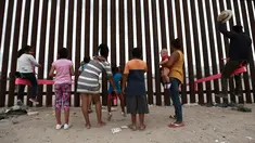 Anak-anak bermain jungkat-jungkit yang dipasang di antara pagar pemisah Meksiko dengan Amerika Serikat, Ciudad de Juarez, Meksiko, Minggu (28/7/2019). Jungkat-jungkit tersebut dirancang seorang profesor arsitektur California, Ronald Rael. (AP Photo/Christian Chavez)