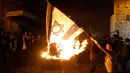 Seorang bocah Yahudi ultra ortodoks antizionis membakar bendera Israel di Yerusalem ultra-Ortodoks Mea Shearim, Rabu (2/5). Hal itu dilakukan selama perayaan Hari Raya Yahudi Lag BaOmer. (MENAHEM KAHANA / AFP)