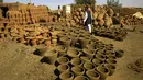 Pot tanah liat dipajang di sebuah bengkel di Omdourman, di pinggiran barat ibu kota Khartoum (19/1/2022). Para perajin tembikar di Sudan memanfaatkan tanah liat sisa banjir untuk membuat benda-benda kerajinan tersebut. (AFP/Ashraf Shazly)