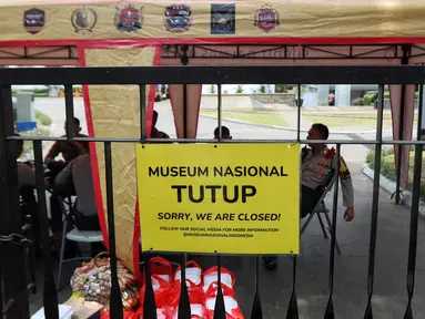 Pemberitahuan penutupan Museum Nasional atau Museum Gajah terpasang pada pagar saat petugas kepolisian berjaga di area Museum Nasional, Jakarta, Minggu (17/9/2023). Pihak Museum Nasional Indonesia mengumumkan bakal tutup sementara usai insiden kebakaran yang berlangsung pada Sabtu (16/9) kemarin. (Liputan6.com/Angga Yuniar)