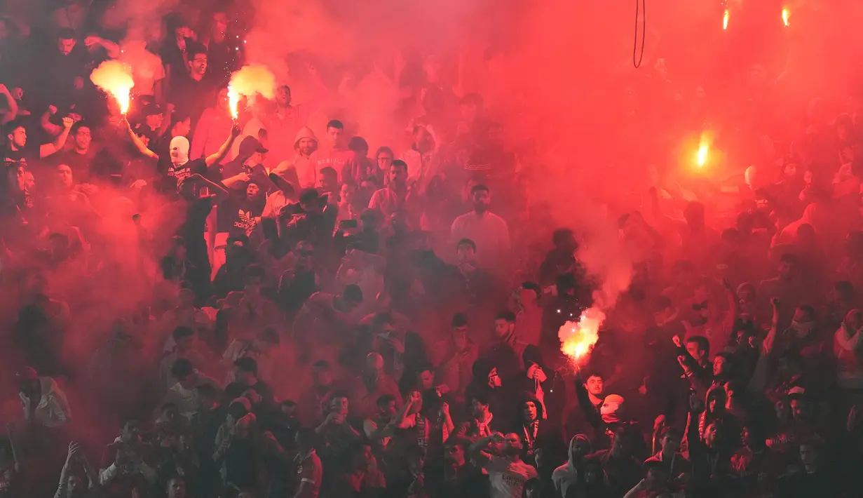 Suporter Benfica menyalakan flare saat laga leg pertama babak perempatfinal Liga Champions 2022/2023 antara Benfica menghadapi Inter Milan di Luz Stadium, Benfica, Rabu (12/4/2023) dini hari WIB. (AP Photo/Armando Franca)