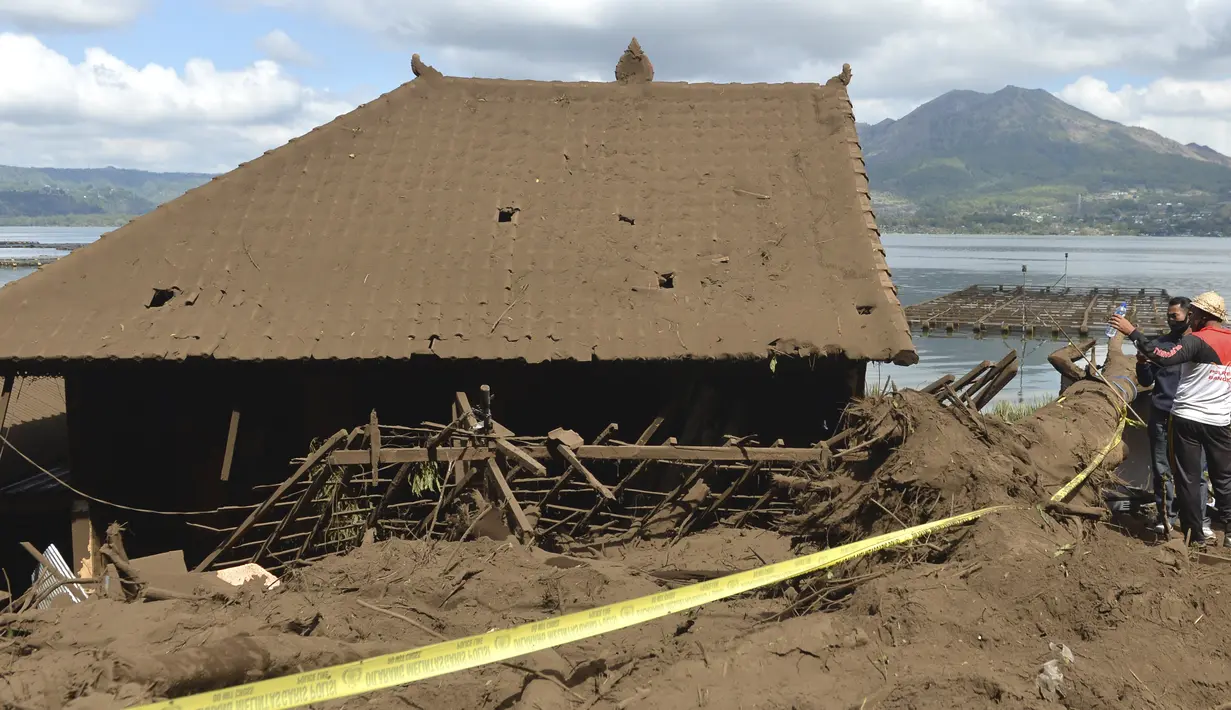 Petugas kepolisian memeriksa rumah yang tertutup lumpur yang rusak akibat longsor akibat gempa di Bangli, Bali, Sabtu (16/10/2021). Beberapa orang tewas dan lainnya luka-luka saat gempa berkekuatan sedang dan gempa susulan menghantam pulau itu Sabtu dini hari. (AP Photo/Dewa Raka)
