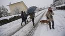 Orang-orang berjalan dengan anjing mereka di salju di Burguete, Spanyol utara, Senin, 16 Januari 2023. Pihak berwenang telah mengumumkan salju dan suhu sangat rendah selama beberapa hari ke depan di seluruh bagian utara negara itu. (AP Photo/Alvaro Barrientos)