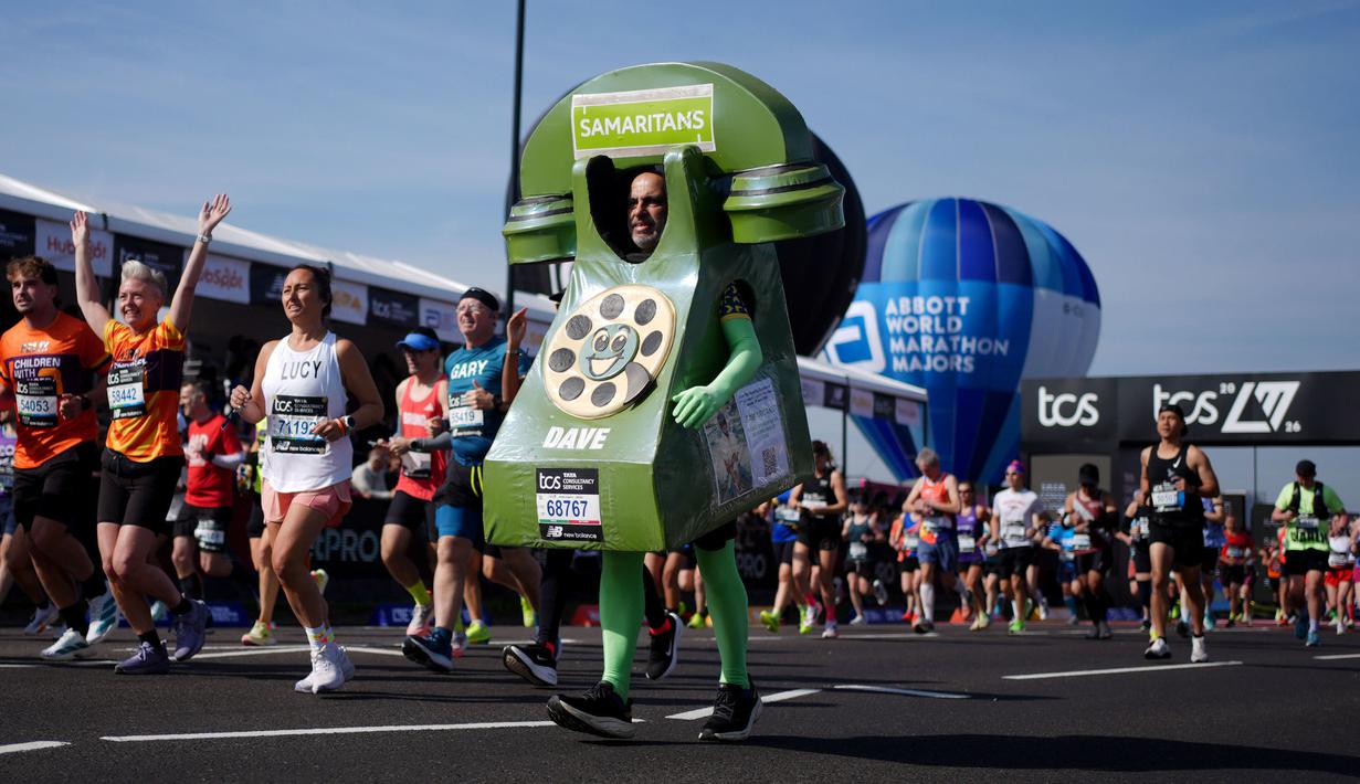 Seorang pelari berkostum telepon konvensional saat berkom dalam London Marathon 2026 di London, Inggris, Minggu (26/04/2026) waktu setempat. (AP Photo/PA/Ben Whitely)