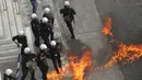 Polisi menghindari api saat bentrok dengan pengunjuk rasa di Athena, Rabu (17/5). Para pekerja meninggalkan lapangan kerja untuk melakukan pemogokan umum anti-penghematan. (AP Photo / Thanassis Stavrakis)