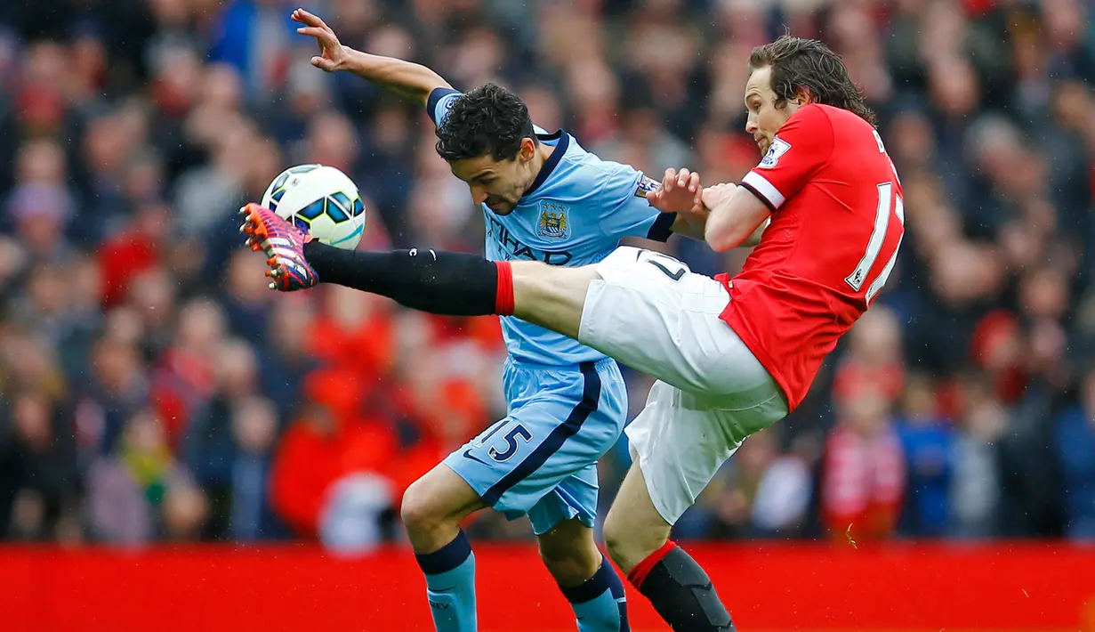 Gelandang Manchester City, Jesus Navas (kiri) berebut bola dengan gelandang Manchester United Daley Blind saat Laga Liga Premier Inggris di Old Trafford, Minggu (12/4/2015). Manchester United menang 4-2 atas City. (Reuters/Darren Staples)