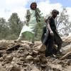 Penduduk desa mengumpulkan barang-barang dari bawah puing-puing sebuah rumah yang hancur akibat gempa bumi di Distrik Spera, bagian barat daya Provinsi Khost, Afghanistan, 22 Juni 2022. Gempa menewaskan lebih dari 1.000 orang dan melukai 1.500 lainnya. (AP Photo)