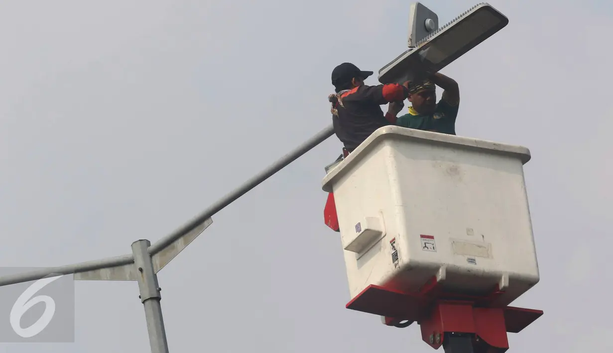 Pekerja memasang lampu light emitting diode (LED) di Jakarta, Selasa (26/7). Secara bertahap, Pemprov DKI akan menggunakan lampu LED yang lebih hemat energi untuk Penerangan Jalan Umum (PJU) di seluruh Jakarta. (Liputan6.com/Immanuel Antonius)